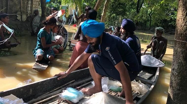 Relief volunteers on wooden boats distributing food packets and essential medical supplies to marooned families.